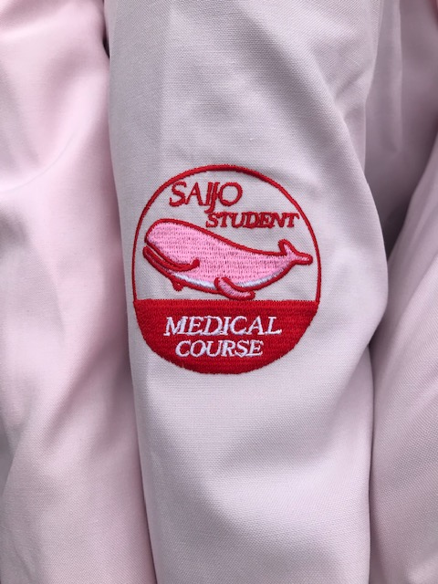 医療系「Student Assistant（スチューデント・アシスタント）」オリジナルロゴです。
「ピンクのくじら🐬」がサポート学生の腕に乗っています！
